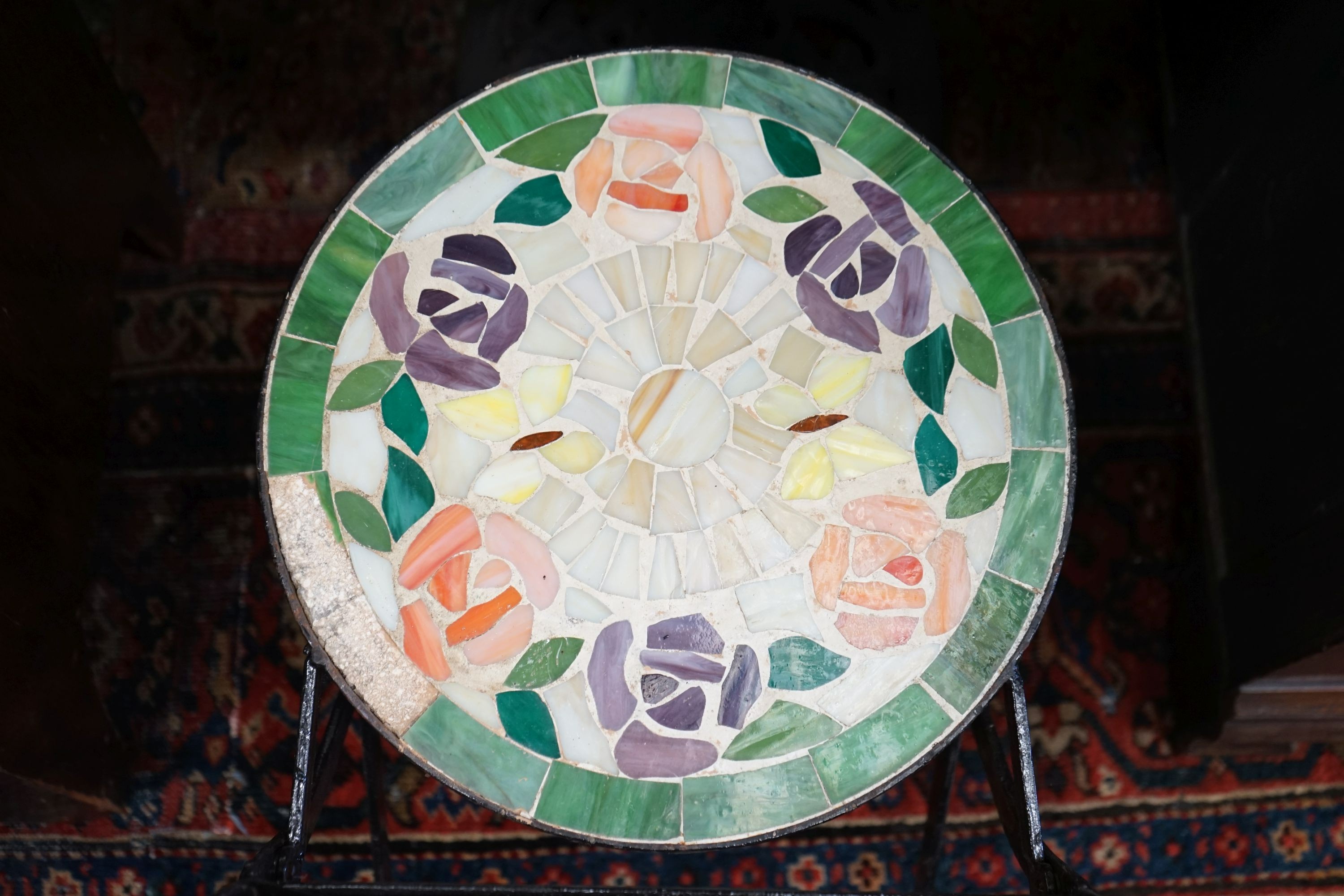 A circular cast iron based garden table, diameter 60cm together with two wrought iron mosaic folding chairs